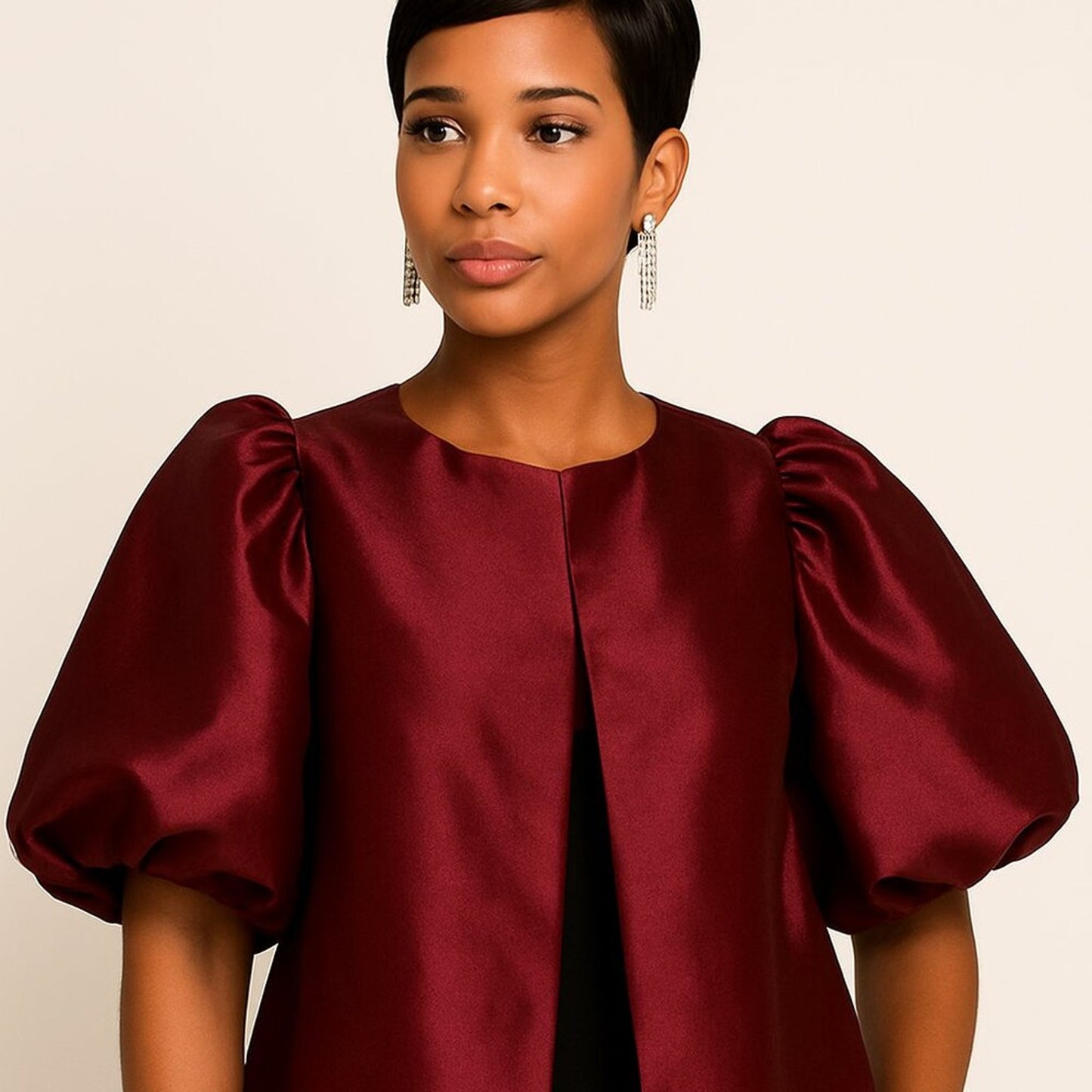 Woman wearing a burgundy satin top with puffed sleeves against a beige background