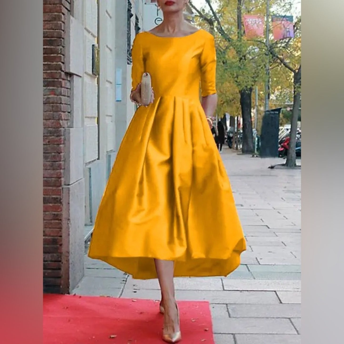 Woman in a yellow dress standing on a red carpet with a city street background
