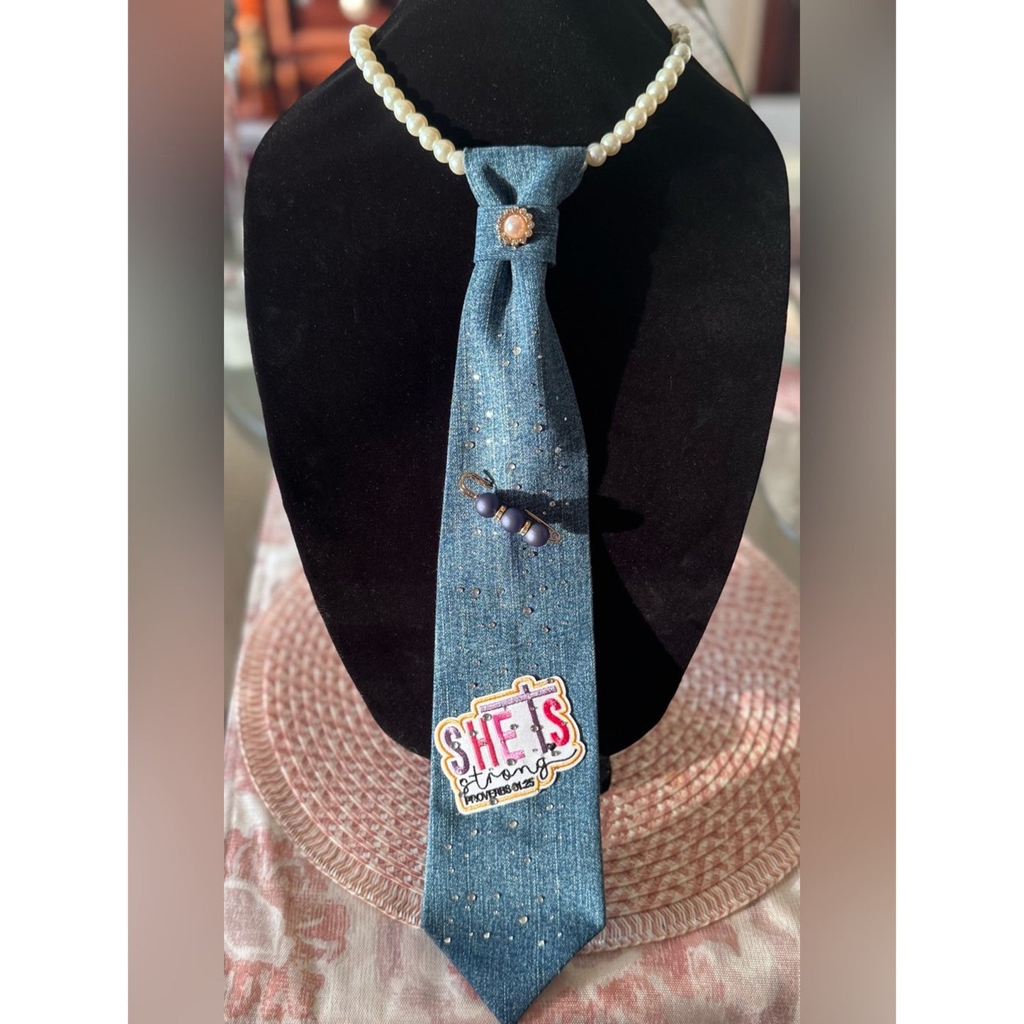 Blue denim tie with a logo on a black mannequin