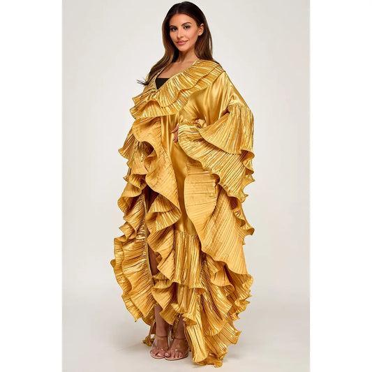 A woman modeling a dramatic, floor-length golden yellow ruffled dress with a metallic sheen, photographed against a neutral light gray studio background.