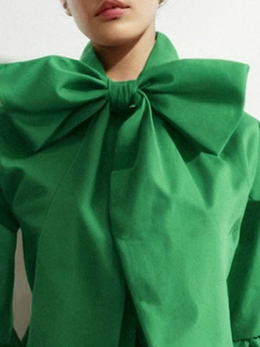 Green blouse with a large bow detail on a plain background