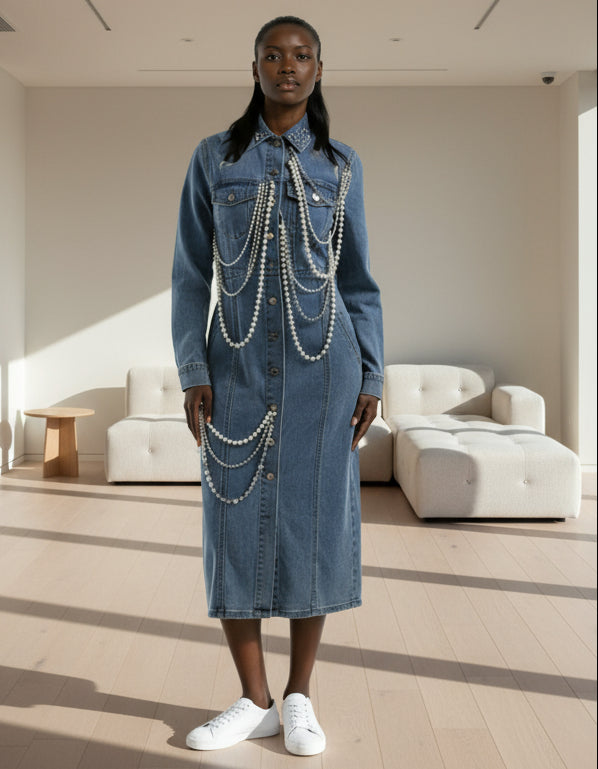 Person wearing a long denim dress with pearl embellishments on a white background