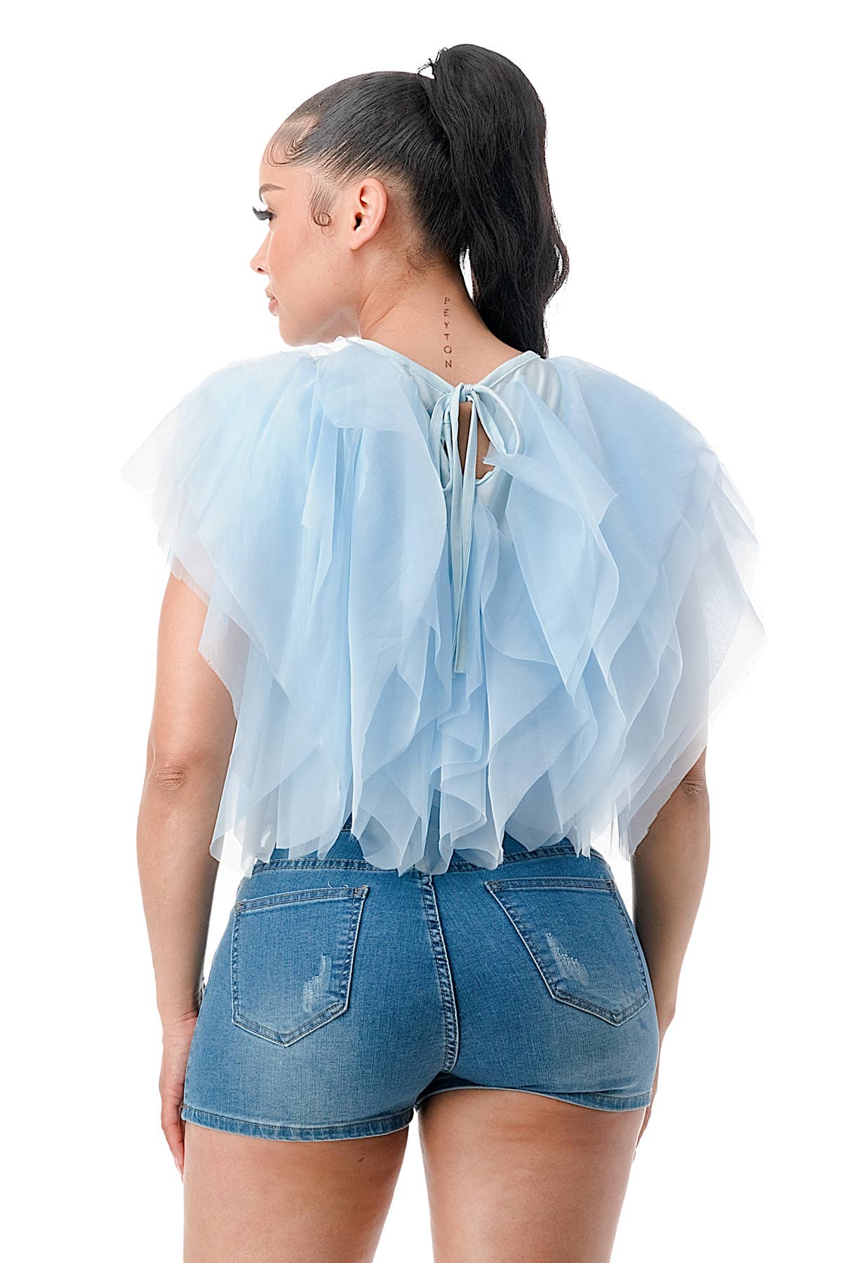 Person wearing a light blue sheer top with denim shorts on a white background