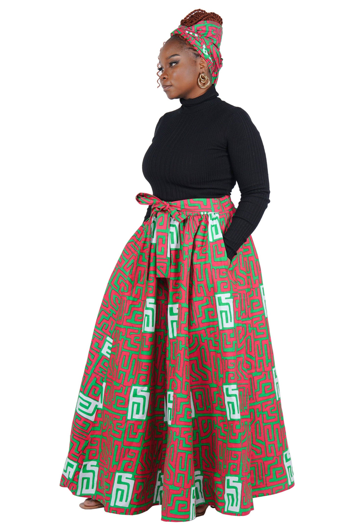 Woman wearing a black top and red and green patterned skirt on a white background