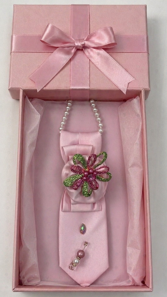 Pink bow tie with decorative brooch and necklace in a pink box on a white background