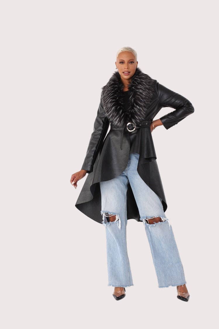 Woman wearing a long black coat with a fur collar and light blue jeans on a white background