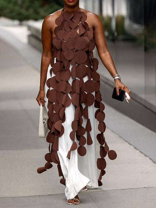 Woman wearing a unique dress with brown circular patterns on a blurred outdoor background