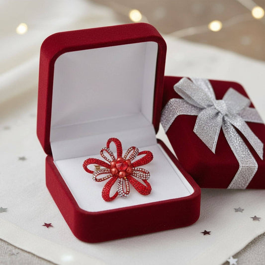 Red flower-shaped brooch in a red velvet box with a silver bow on a light background