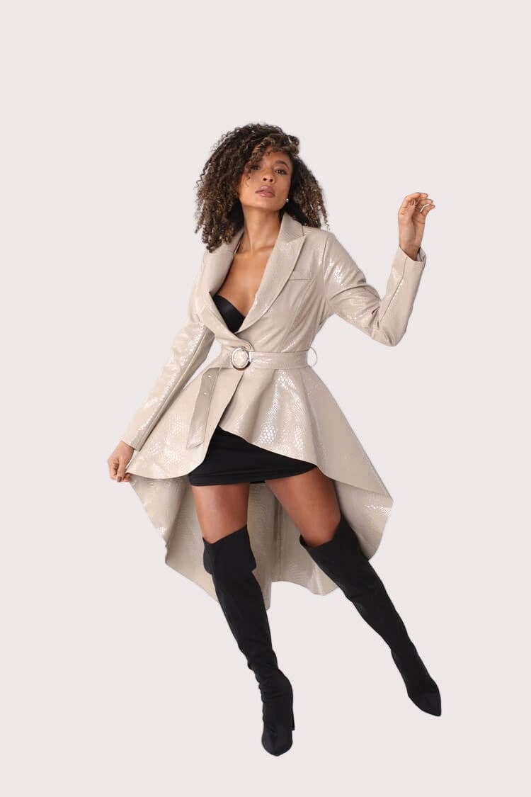 Woman wearing a silver metallic trench coat over a black dress on a white background