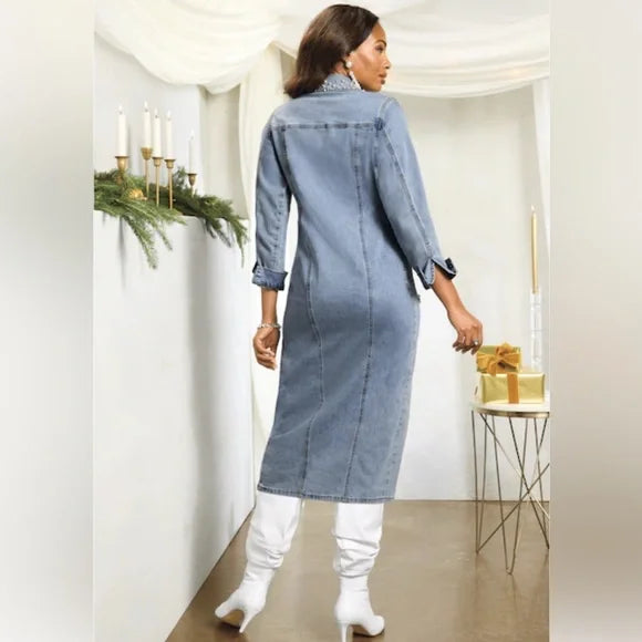 Woman wearing a denim dress in a decorated room with candles and greenery.