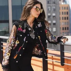Woman wearing a black floral embroidered jacket on a rooftop with cityscape background