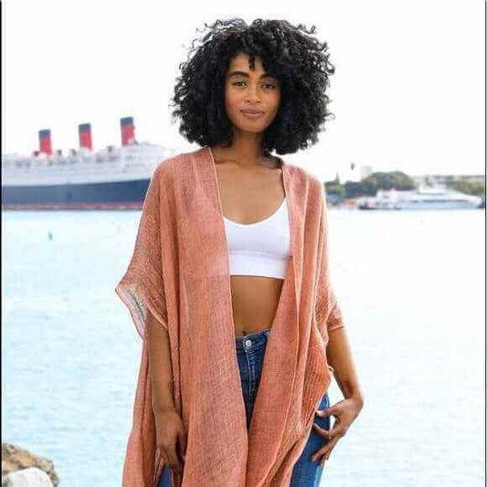 Woman wearing boho-chic kimono layered over casual summer outfit with linen pants