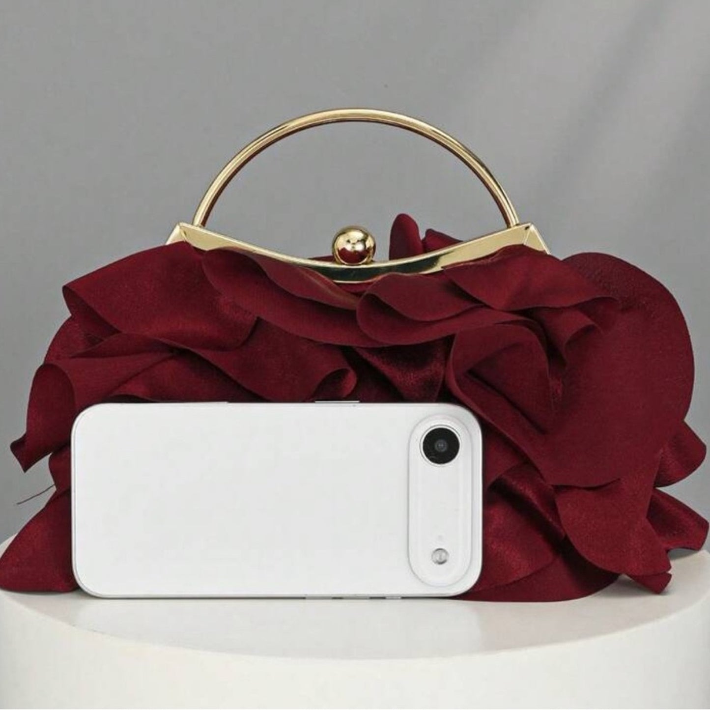 Red floral handbag with a white phone on a gray background