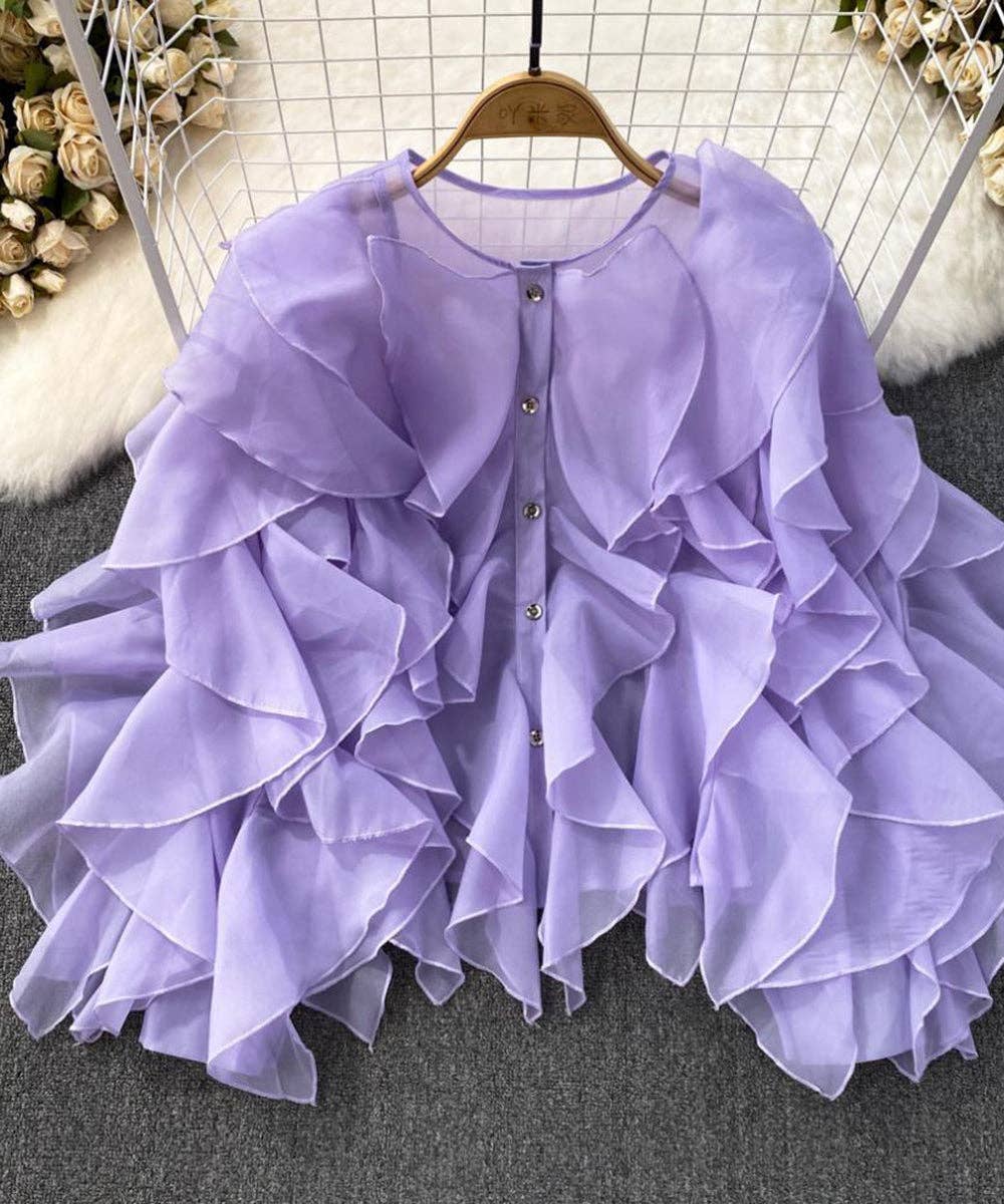 Purple ruffled blouse on a hanger with a soft focus background