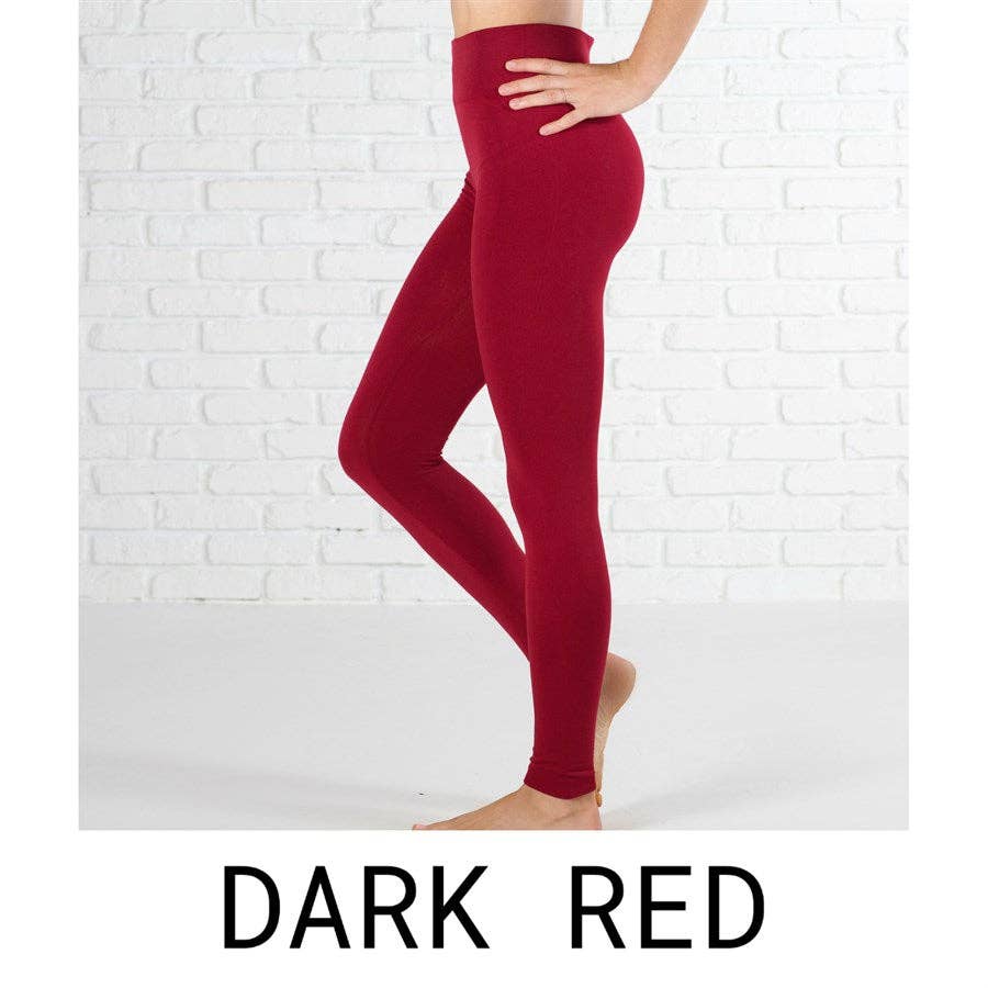 Dark red leggings worn by a person on a white brick wall background