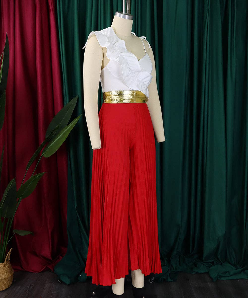 Mannequin wearing a white top with ruffles, gold waistband, and red pleated pants against a green and red curtain background.