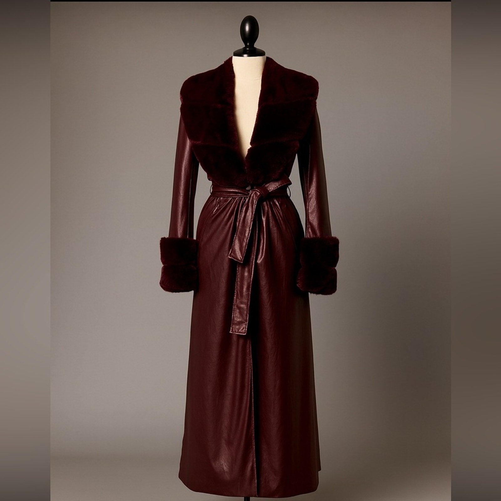 Brown leather coat with fur trim on a mannequin against a plain background