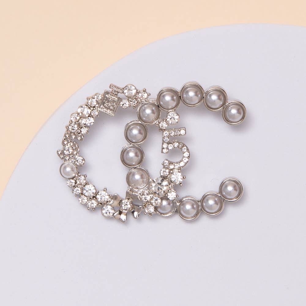 Decorative brooch with pearls and crystals on a light background