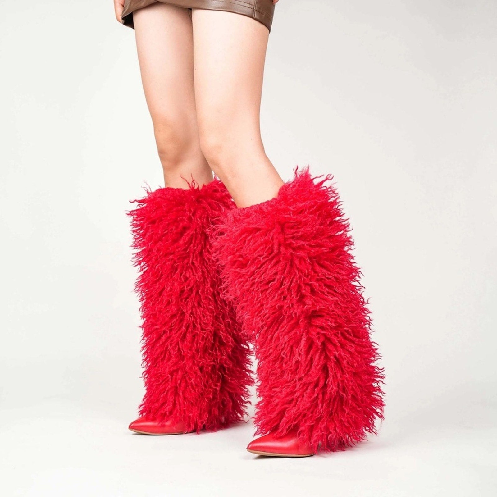Red furry boots worn by a person on a white background