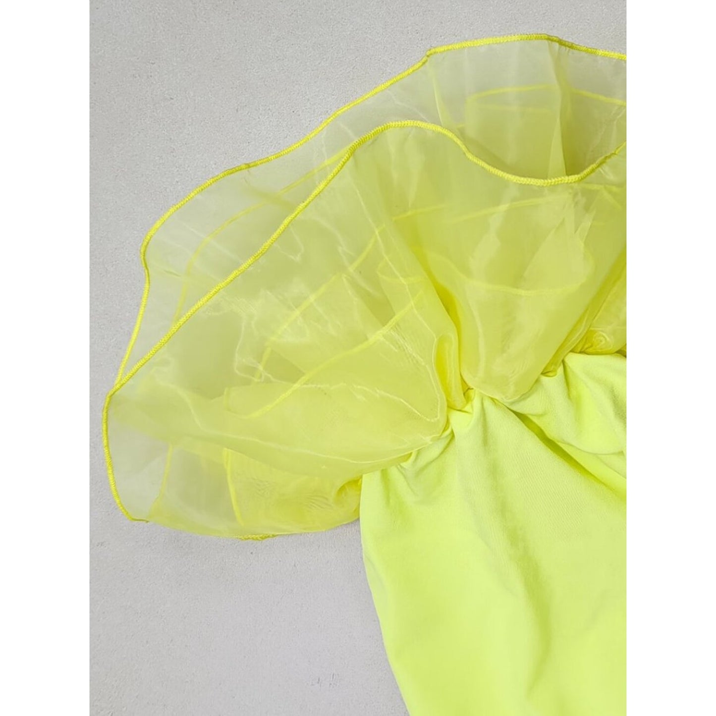 Yellow fabric with ruffled edge on a light gray background