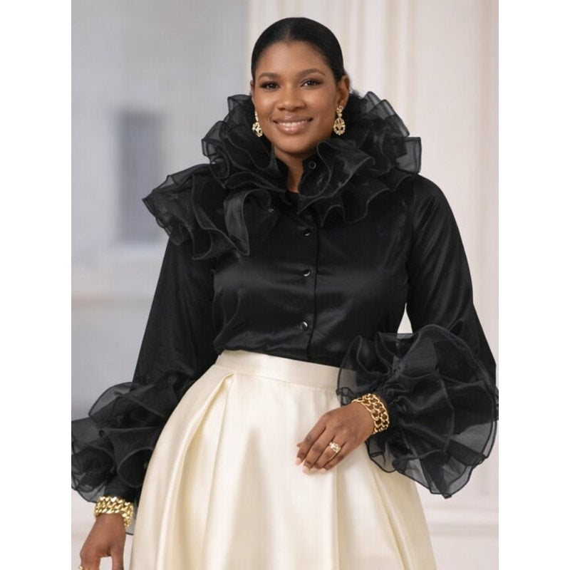 Woman wearing a black blouse with ruffled sleeves and a white skirt.