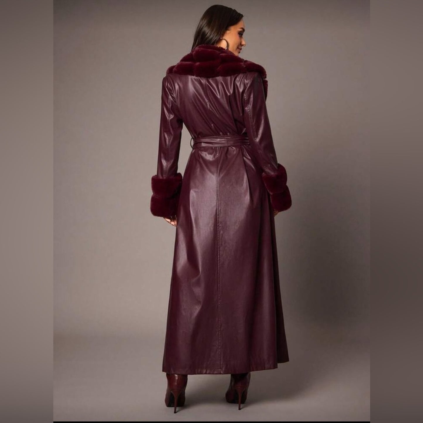Long burgundy coat with fur trim worn by a model on a plain background