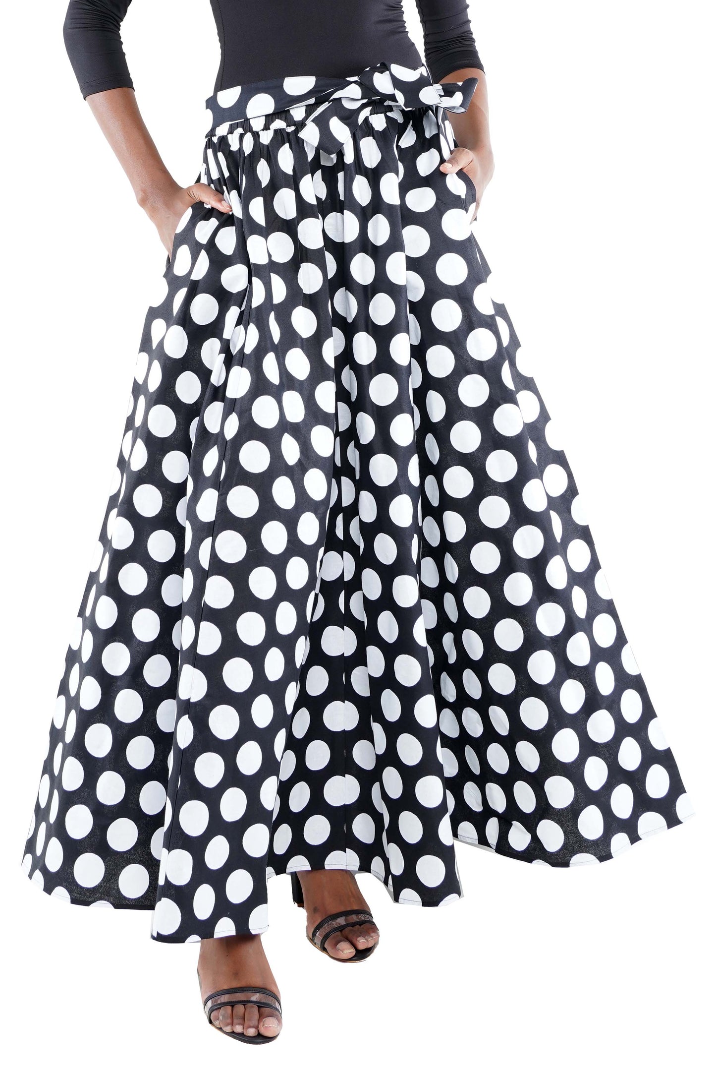 Person wearing a black and white polka dot skirt on a white background