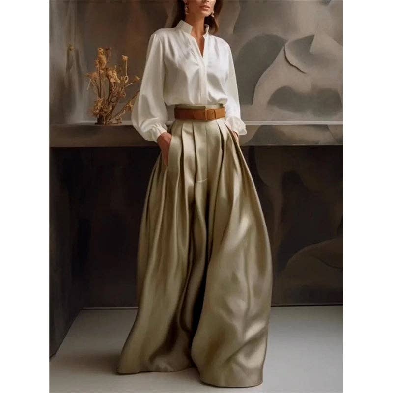 Person wearing a white blouse and beige wide-leg pants with a brown belt, standing against a neutral background.