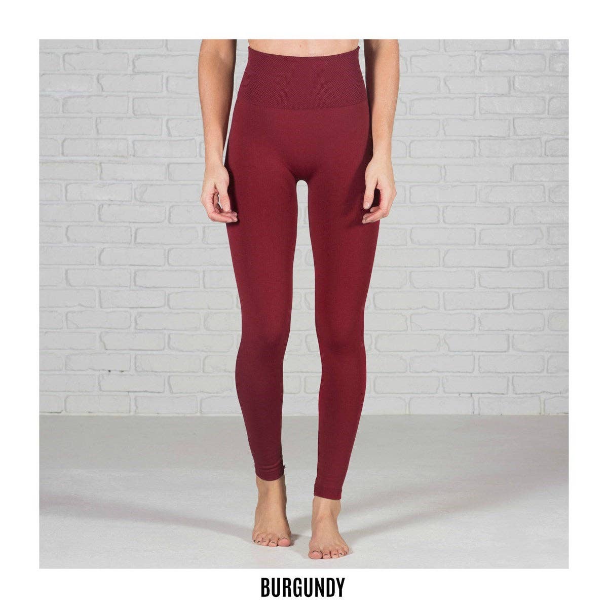 Burgundy leggings worn by a person against a white brick wall.