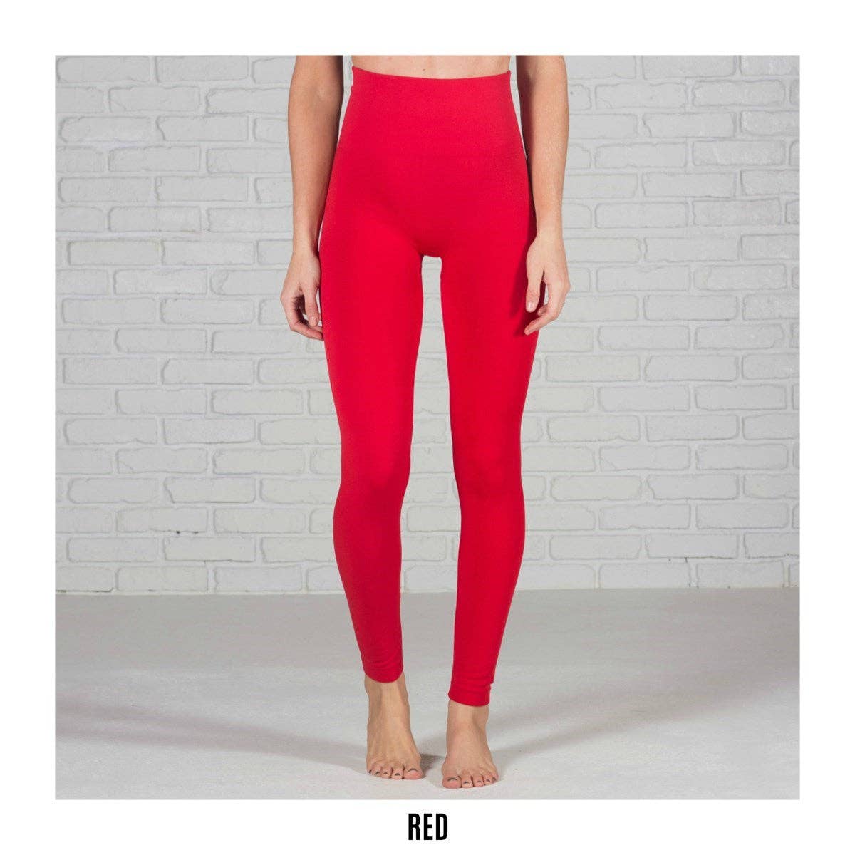 Red leggings worn by a person against a light gray brick wall.