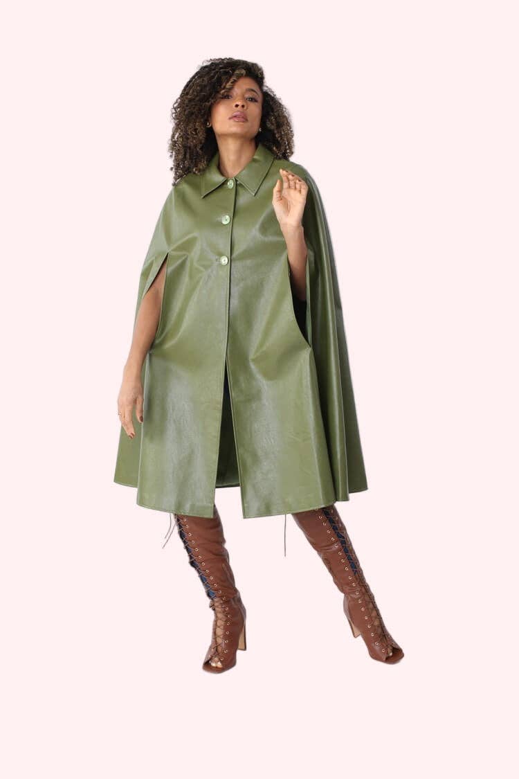 Woman wearing a green leather cape over a dress on a white background