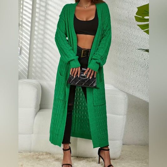 Person wearing a long green cardigan over a black outfit with a white background