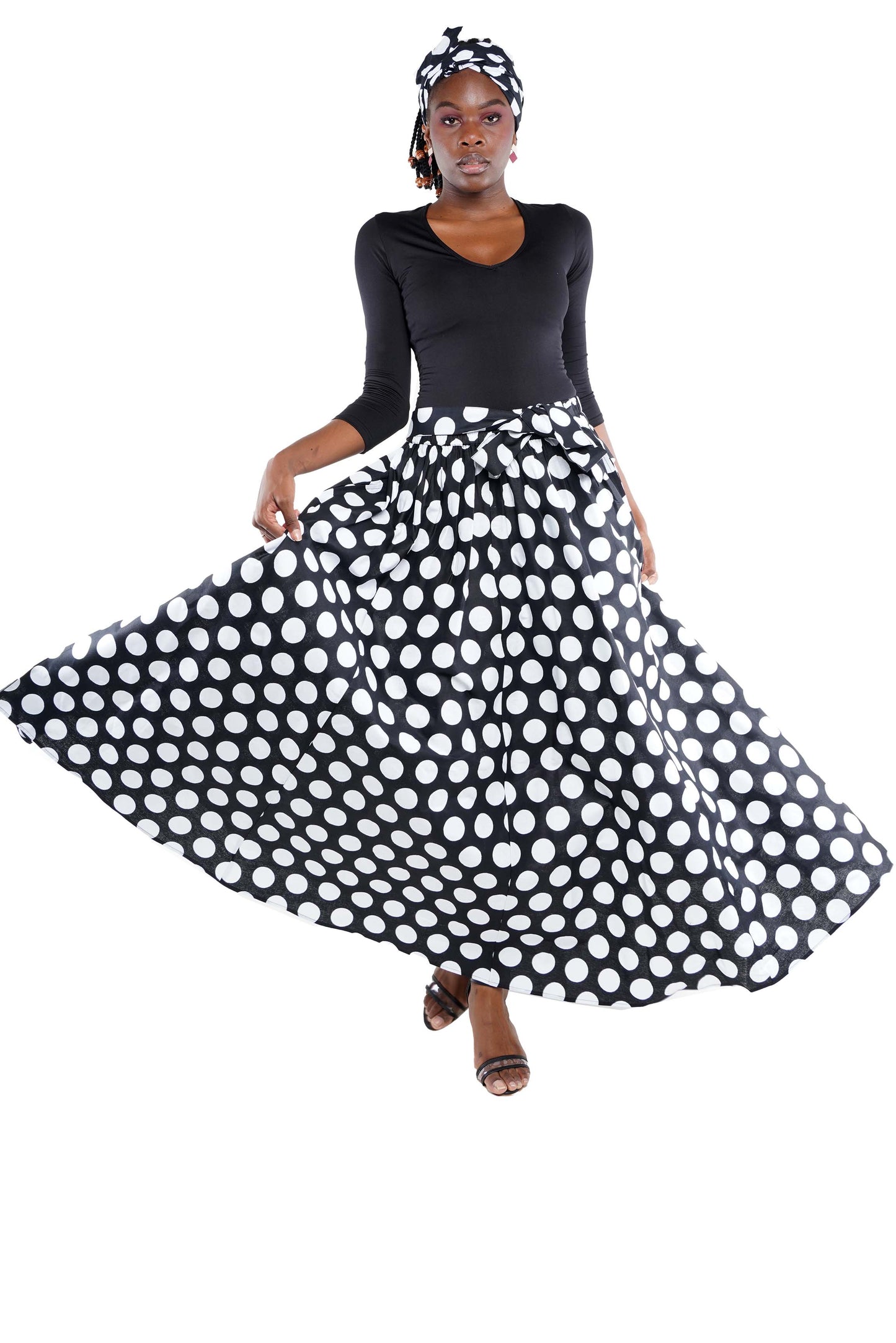 Woman wearing a black top and polka dot skirt on a white background