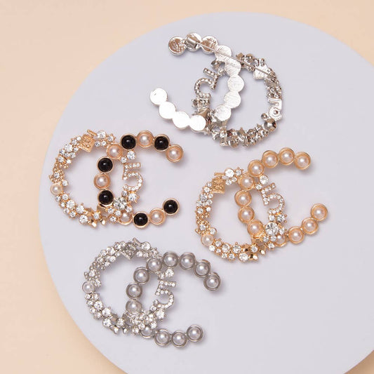 Set of five pearl and crystal bracelets on a light gray plate with a beige background