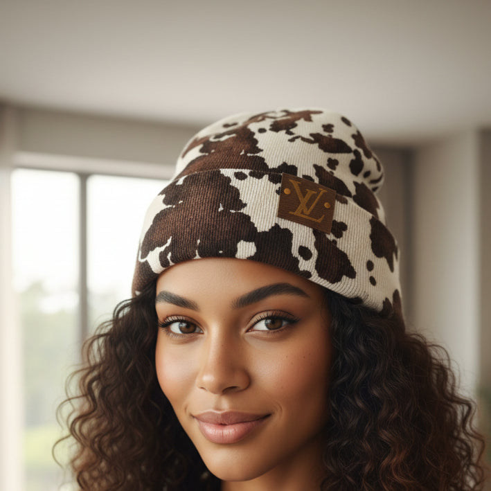 Cow print beanie with a logo on a white background