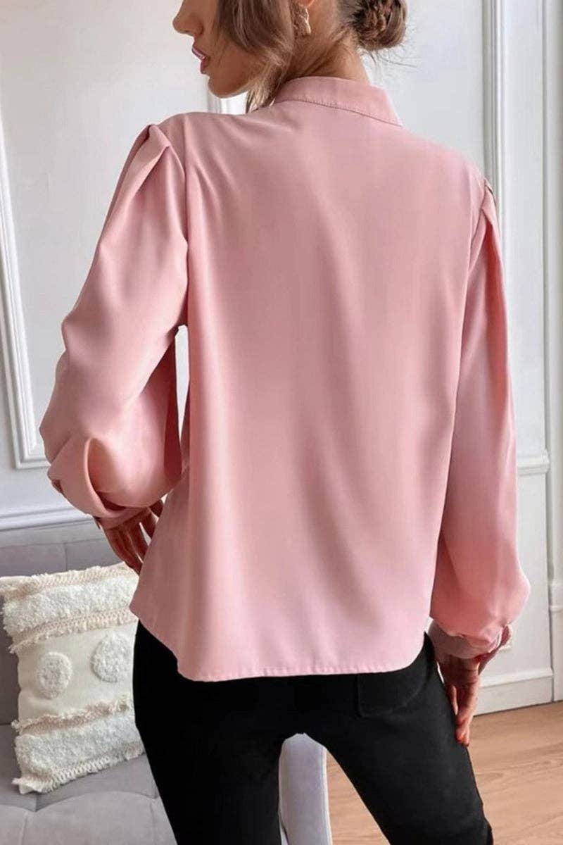 Person wearing a light pink blouse in an indoor setting