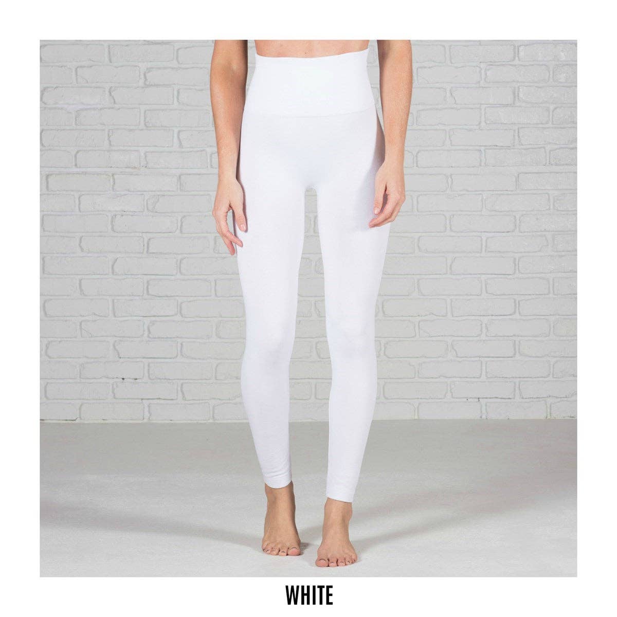 White leggings worn by a person against a light gray brick wall.