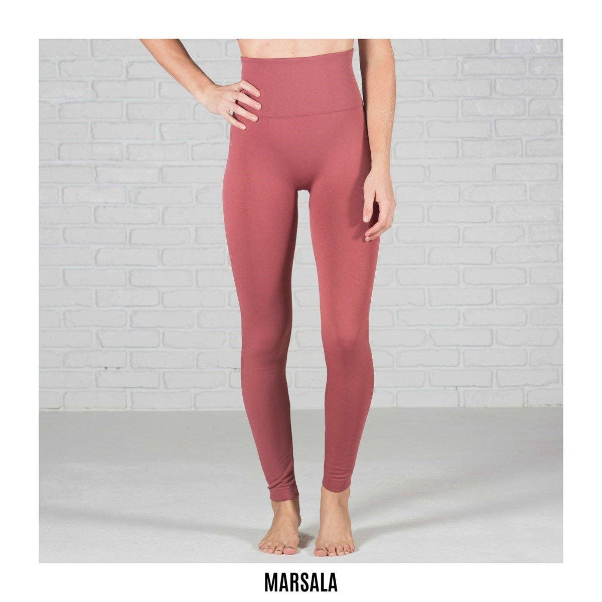 Person wearing maroon leggings against a white brick wall