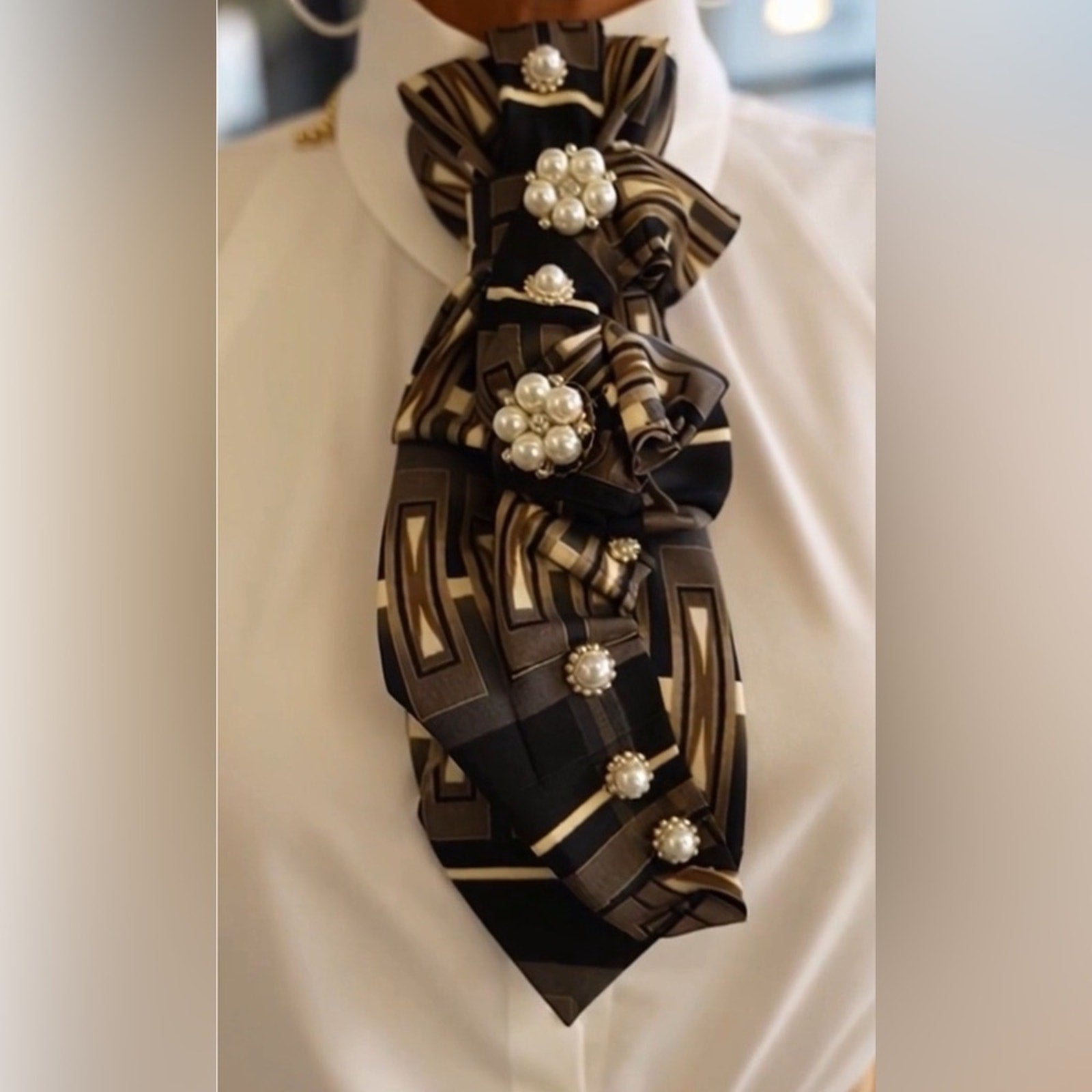 Close-up of a decorative scarf with pearl-like embellishments on a white background