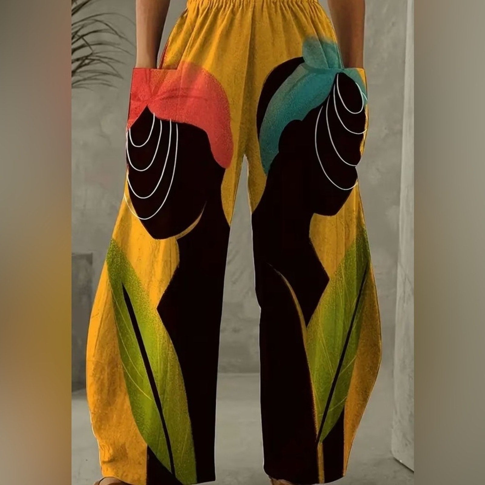 Yellow pants with artistic black figures and colorful accessories on a neutral background