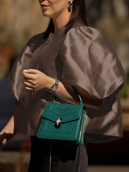 Woman holding a teal handbag with a blurred background