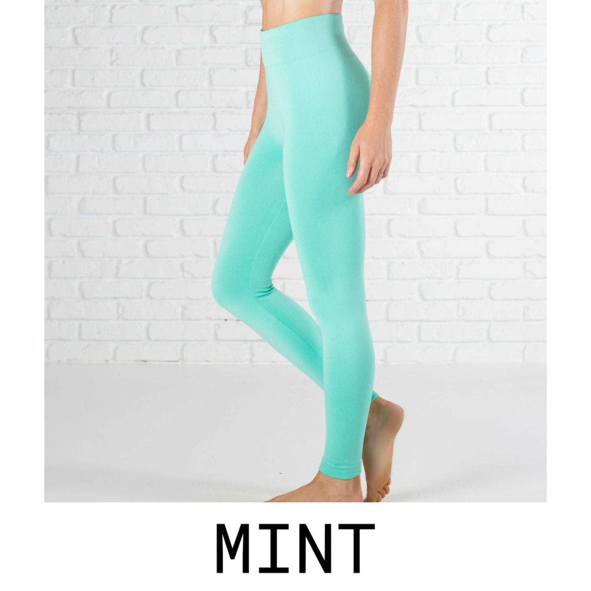 Mint green leggings worn by a person on a white brick wall background
