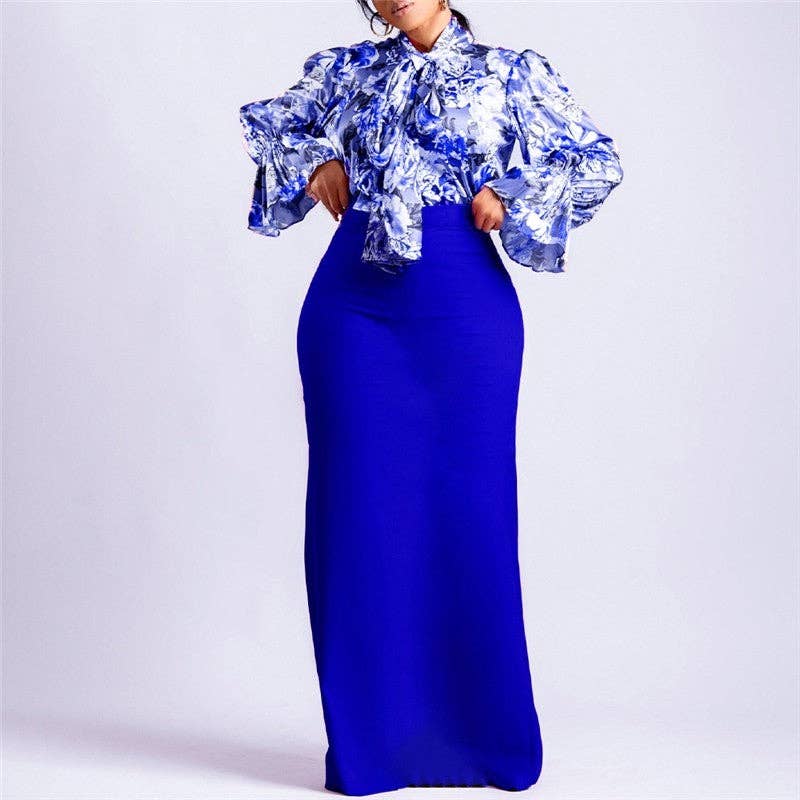 Woman wearing a blue and white floral top with a long blue skirt on a light gray background