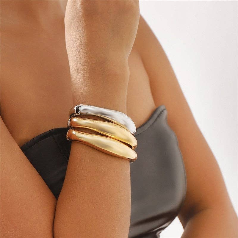 Gold and silver bracelet on a wrist with a blurred background