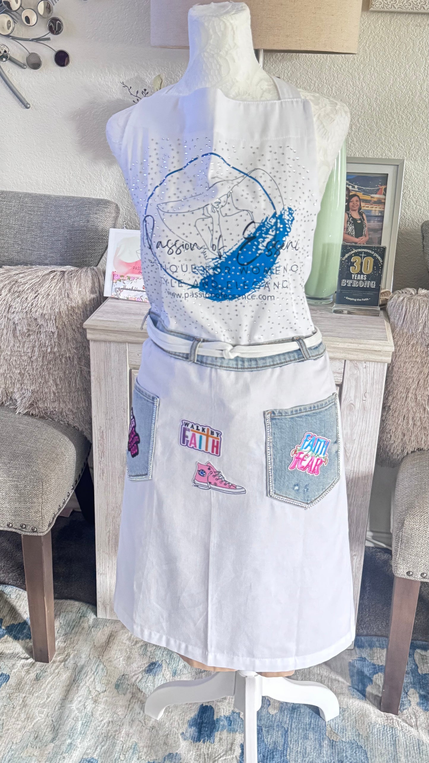 White apron with colorful patches on a mannequin in a room setting.