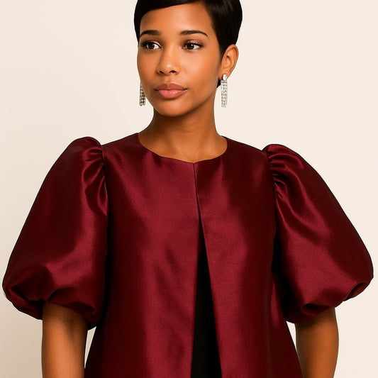 Woman wearing a burgundy satin top with puffed sleeves against a beige background