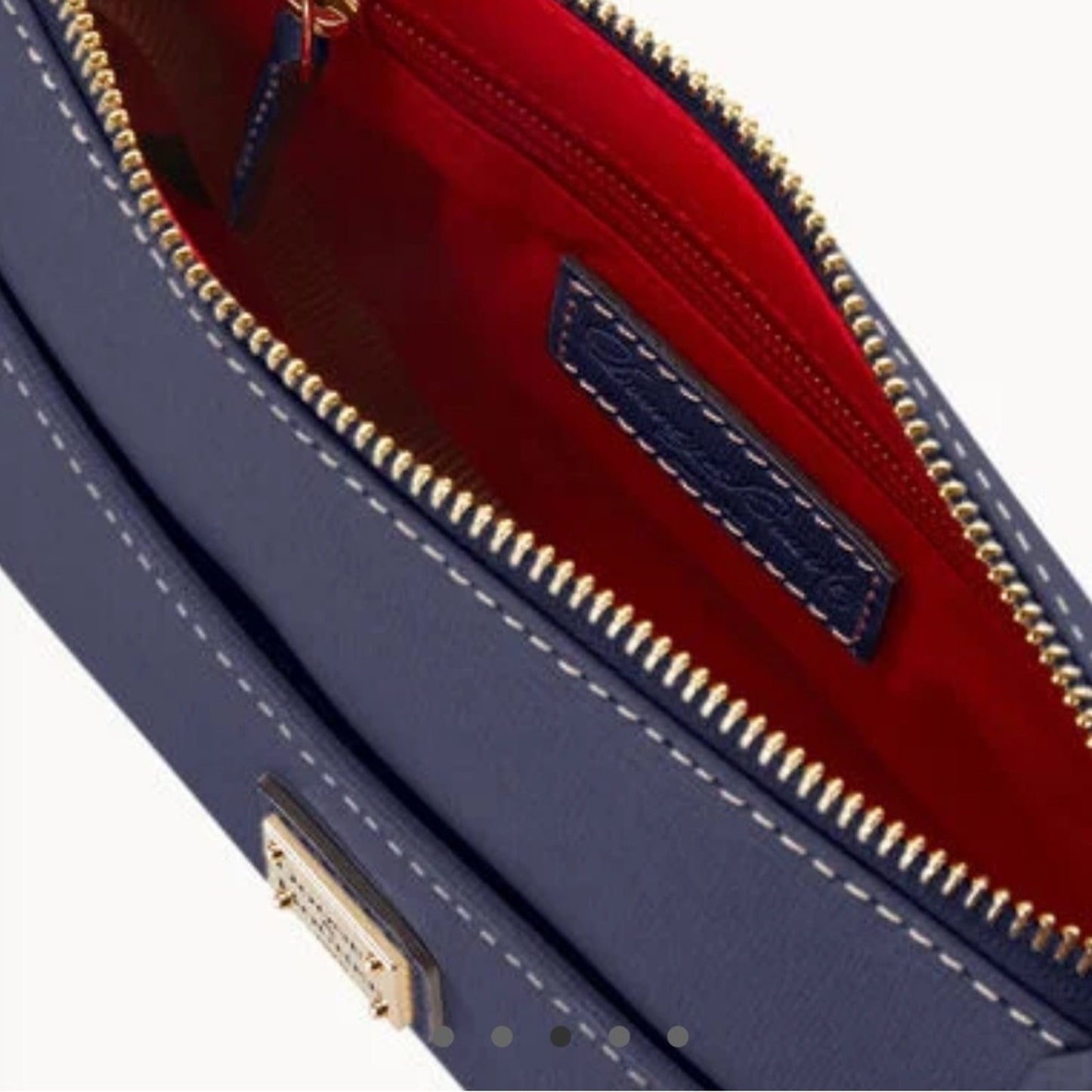 Close-up of a blue handbag with gold zipper and red interior
