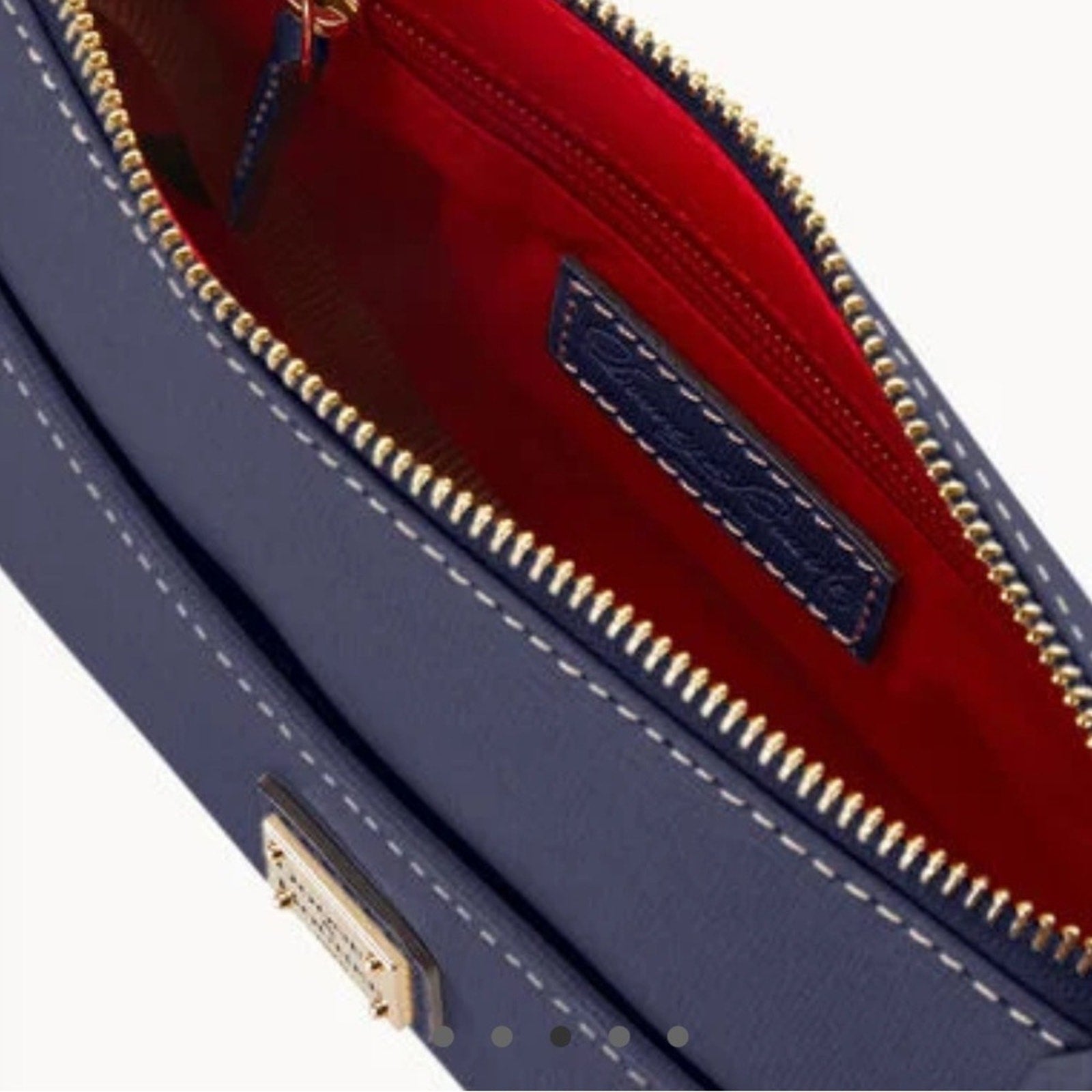 Close-up of a blue handbag with gold zipper and red interior