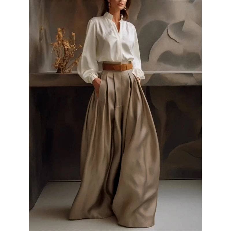 Person wearing a white shirt and beige wide-leg pants with a brown belt, standing against a neutral background.