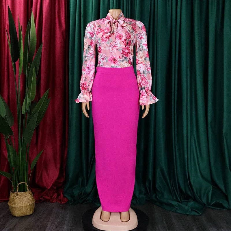 Mannequin wearing a floral blouse and pink skirt against a green curtain background